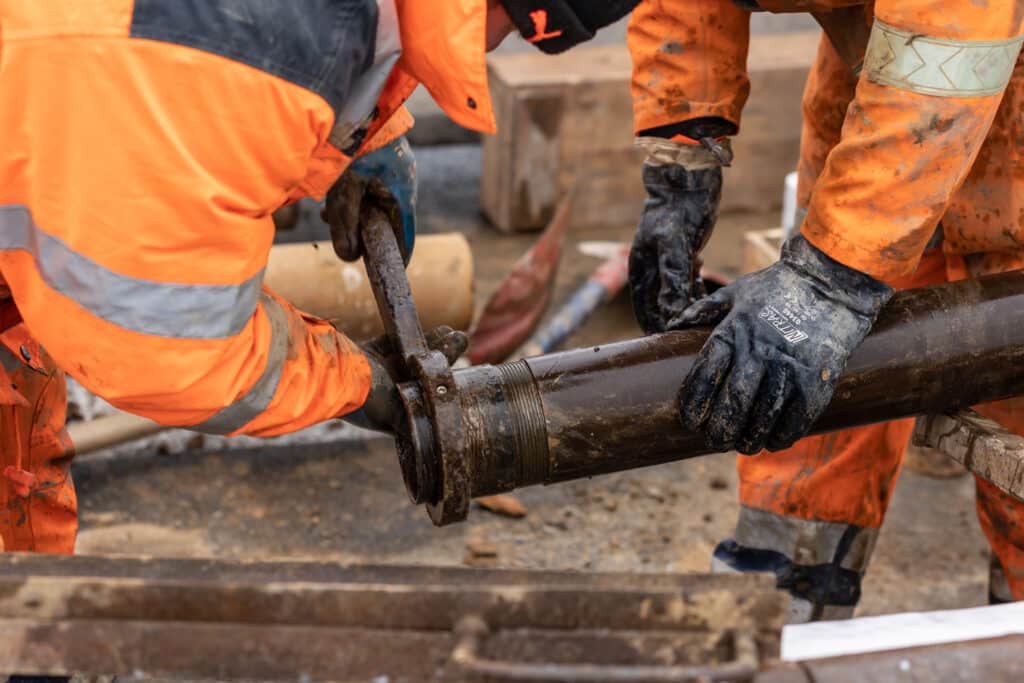 Arbeiter reparieren Rohr auf Baustelle