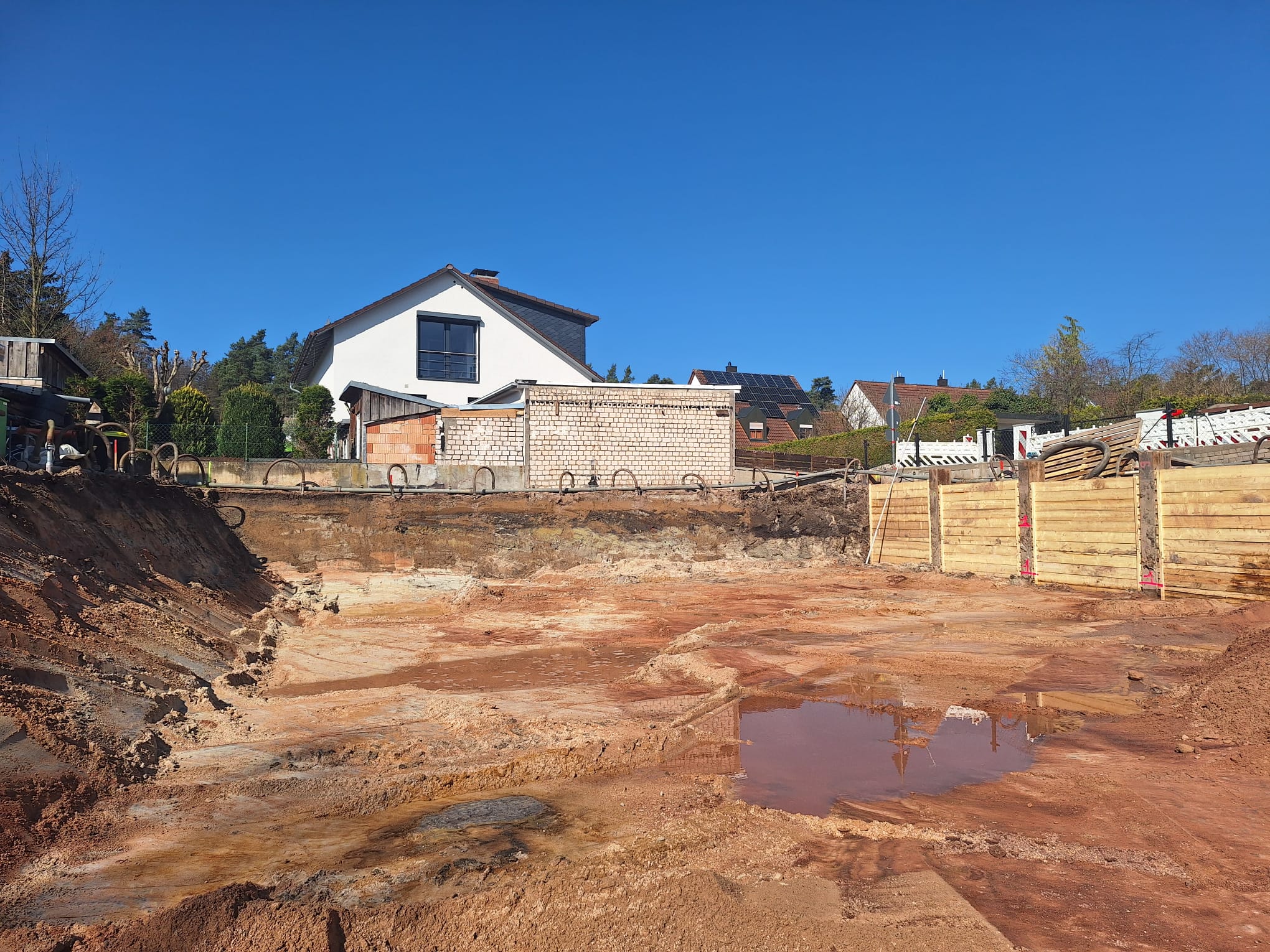 Hausbaugrube mit Wasser und umliegenden Häusern